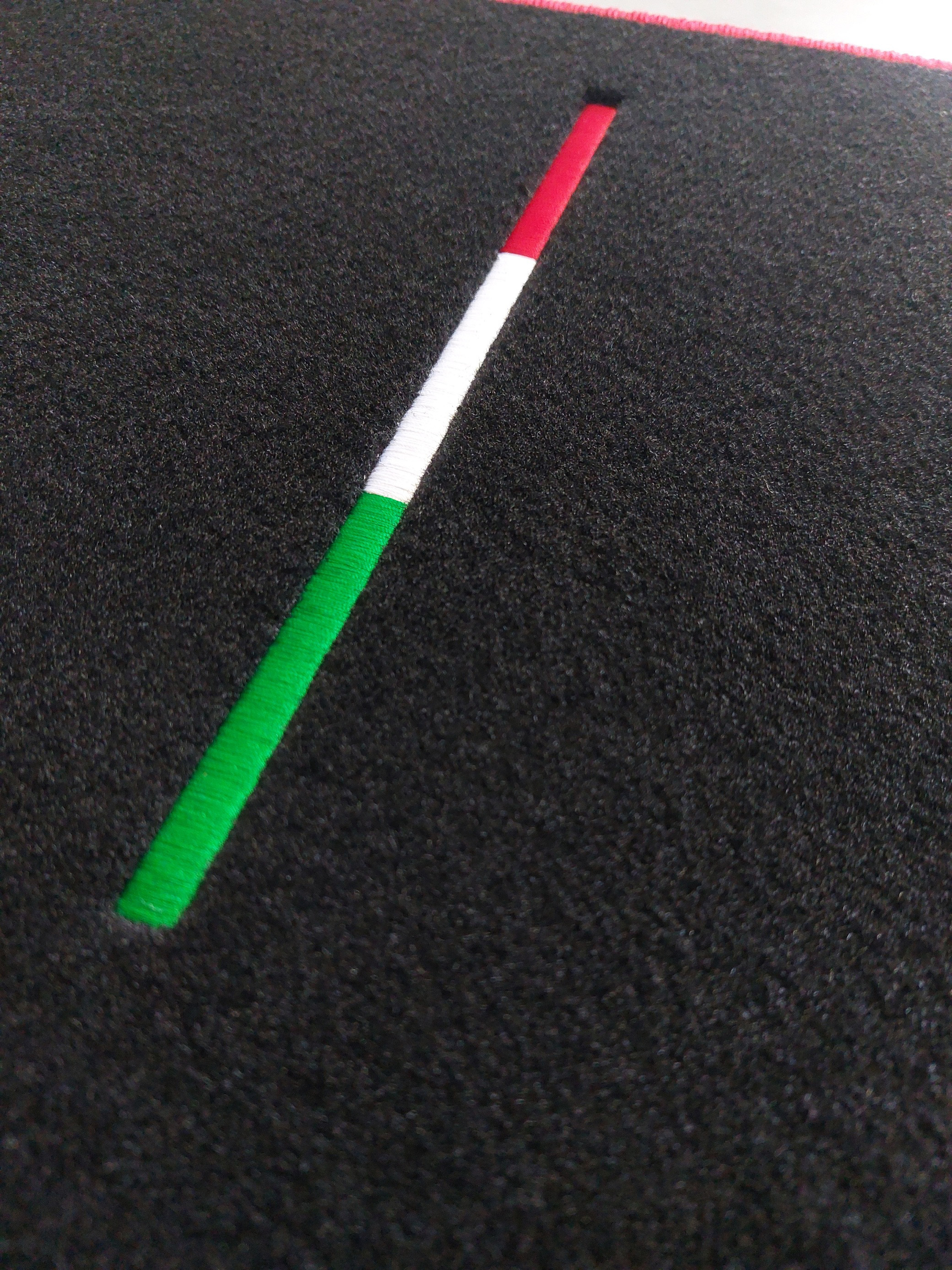 Die italienische Flagge auf einem schwarzen Teppich gestickt.