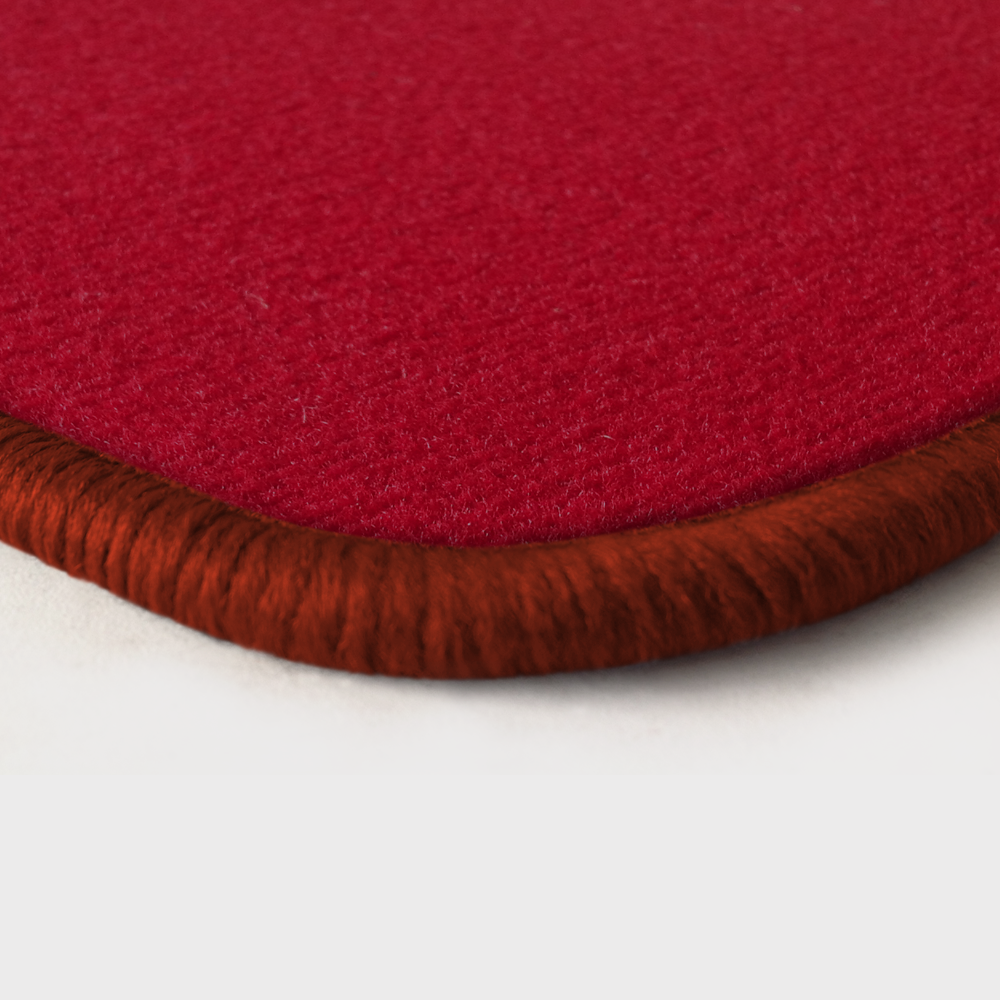 Eine Ecke als Beispiel einer Fussmatte Velours rot mit Rand in kupfer.