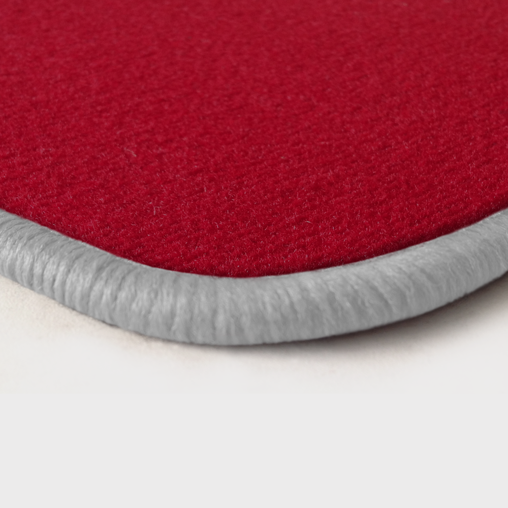 Eine Ecke als Beispiel einer Fussmatte Velours rot mit Rand in weiss.